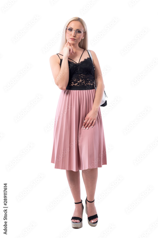 Young blonde smart woman with glasses looking at camera thinking with finger on chin. Full body isolated on white background.