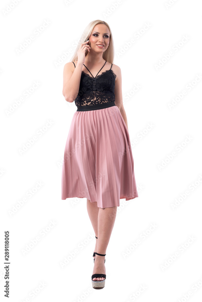 Elegant confident smiling young beautiful woman walks, talks on the phone and looks away. Full body isolated on white background. Elegant confident smiling young beautiful woman walks, talks on the phone and looks away. Full body isolated on white background.