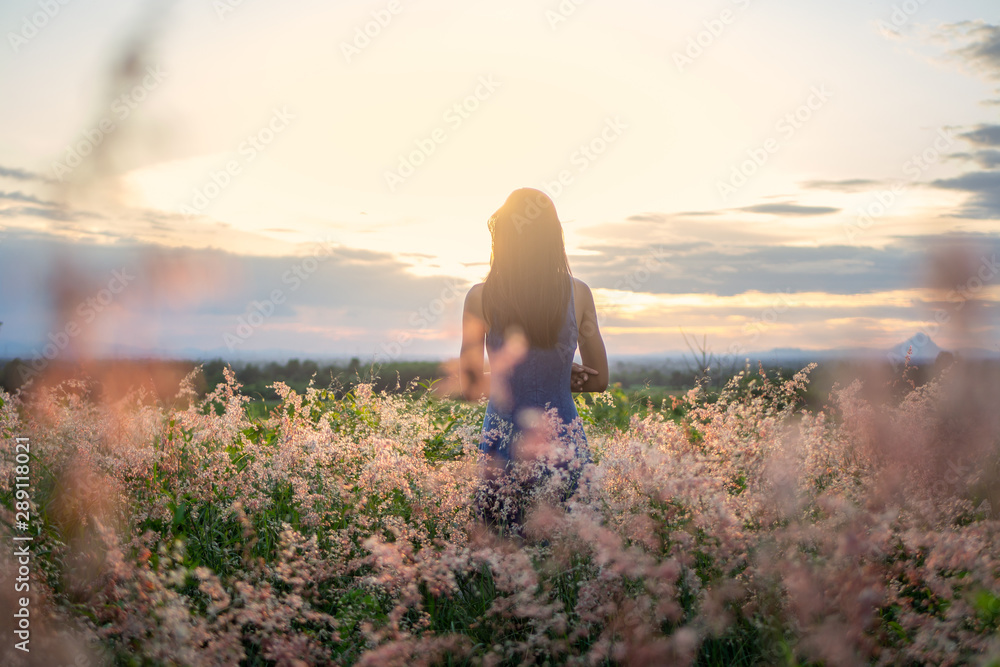 Fototapeta premium Trendy girl in stylish summer dress feeling free in the field with flowers in sunshine.