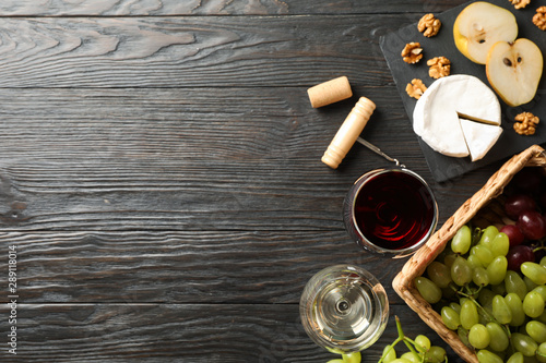 Grape, cheese, walnut, glasses with wine, on wooden background, space for text