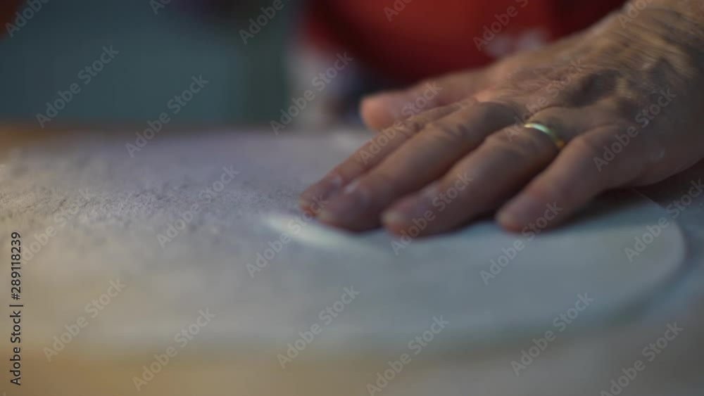Woman chef baker making a pizza shaping a dough on a wooden board with a rolling pin in a restaurant pizzeria or in the kitchen of a house. Food concept. Woman chef baker making a pizza shaping a dough on a wooden board with a rolling pin in a restaurant pizzeria or in the kitchen of a house. Food concept.