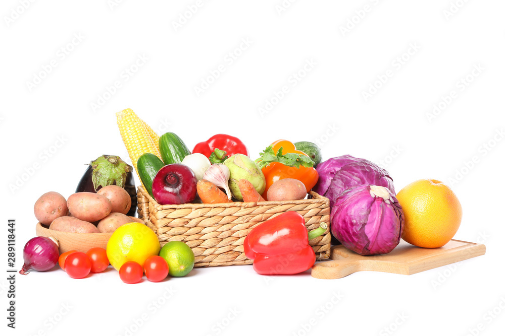 Wicker basket, wood board and vegetables isolated on white background