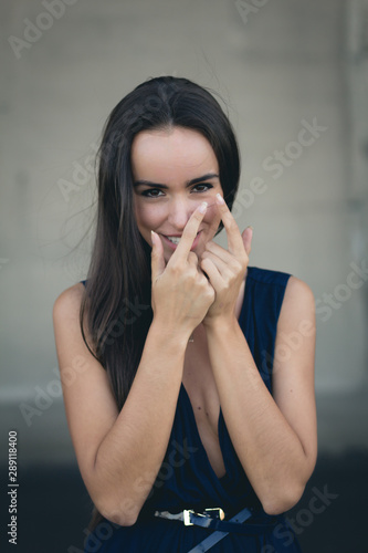 Closeup portrait of a happy young brunette teenage girl outdoor. concrete wall on background
