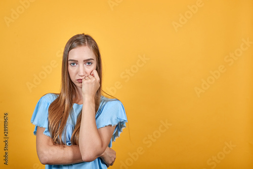 girl brunette in blue t-shirt over isolated orange background shows emotions