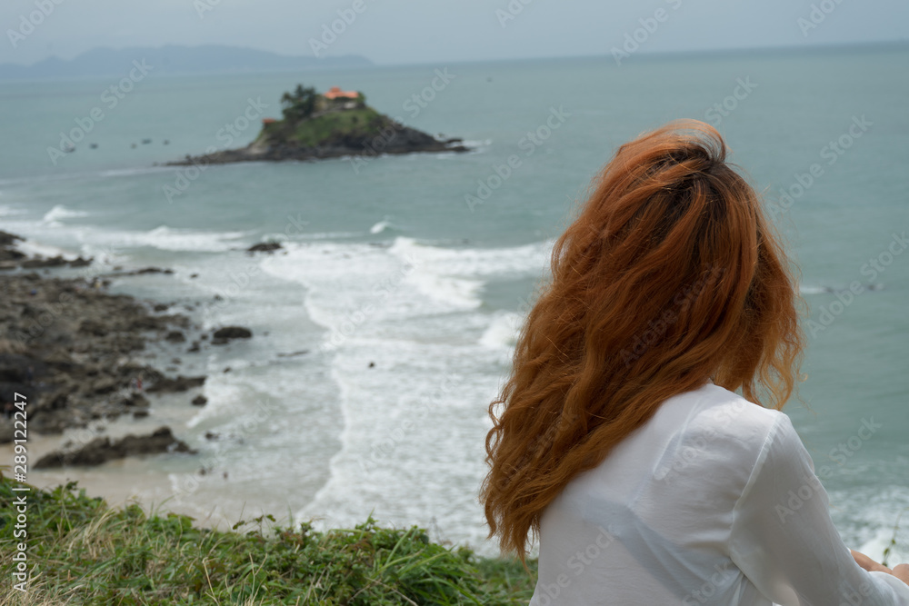 Red haird girl in long white skirt traveler in nature looking to beautiful view and small island in Vung Tau.Relax time on holiday concept travel . Red haird girl in long white skirt traveler in nature looking to beautiful view and small island in Vung Tau.Relax time on holiday concept travel .