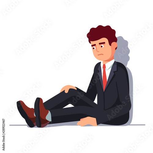 Depressed business man sitting leaning on wall
