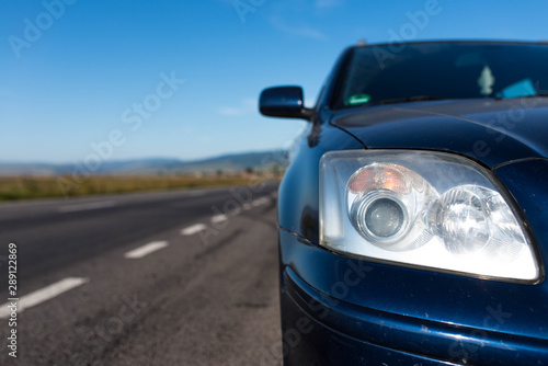 Japanese car headlight on focus near empty asphalt road at summertime . © Alpar