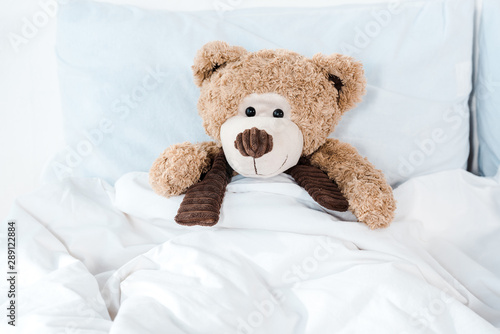 soft toy in bed with white bedding and pillows