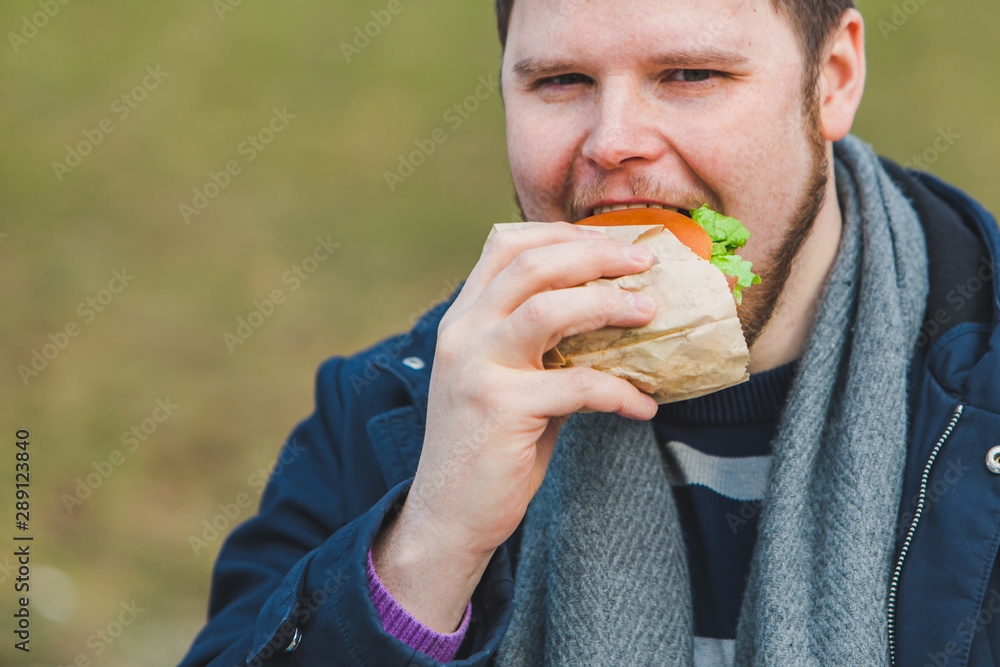 young adult man eating hamburger young adult man eating hamburger