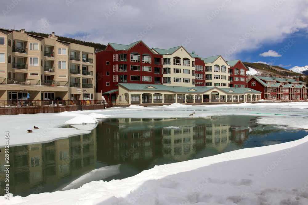 Obraz premium Colorado nature background, ski resort vacation concept. Scenic view with Keystone sky resort downtown and mountains around the covered by snow and thawed ice lake in spring sunlight. 
