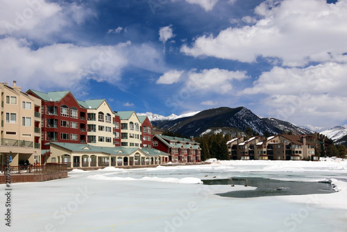 Colorado nature background, ski resort vacation concept. Scenic view with Keystone sky resort downtown and mountains around the covered by snow and thawed ice lake in spring sunlight.  © Maryna