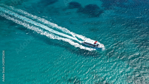 Aerial bird's eye view photo taken by drone of boat cruising in Caribbean tropical beach with turquoise - sapphire waters