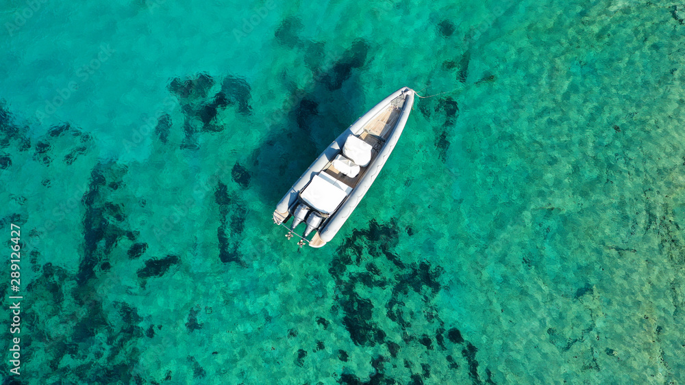 Aerial top view luxury inflatable rib speed boat docked in mediterranean emerald bay with crystal clear sea Aerial top view luxury inflatable rib speed boat docked in mediterranean emerald bay with crystal clear sea