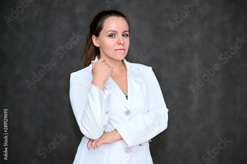 Business Portrait of a pretty female manager on a gray background in a white business suit. Standing right in front of the camera in various poses. © Вячеслав Чичаев