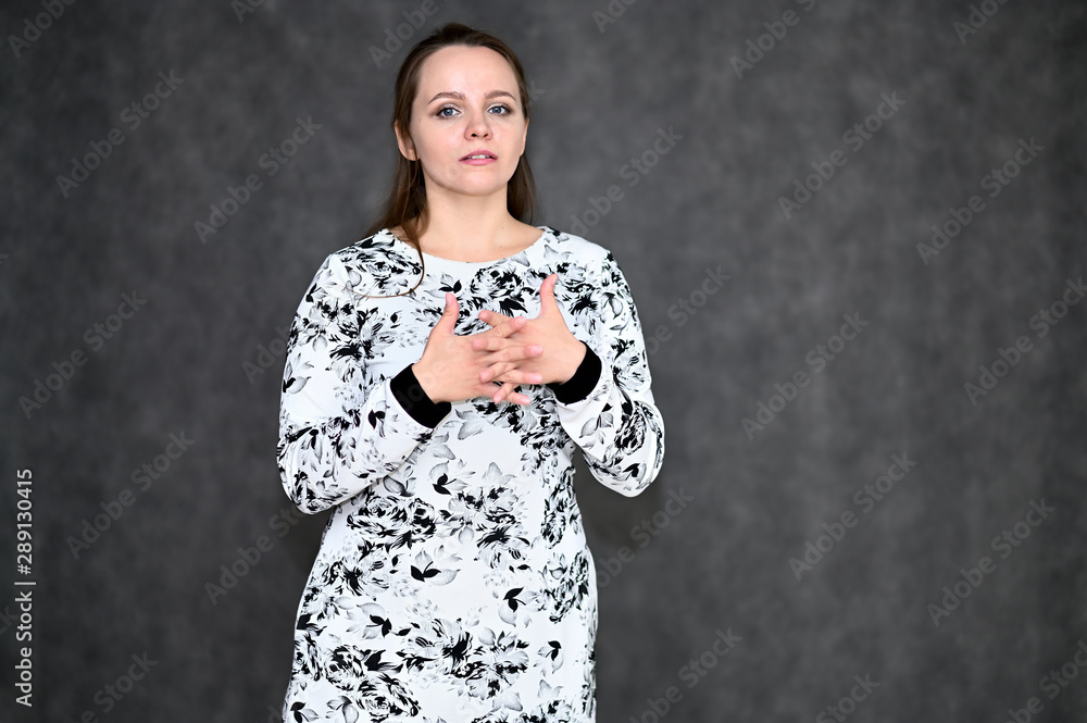 Portrait of a pretty young woman on a gray background in a light dress. Standing right in front of the camera in various poses. Portrait of a pretty young woman on a gray background in a light dress. Standing right in front of the camera in various poses.