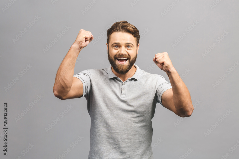 Happy winner. Happy young handsome man gesturing and keeping mouth open while standing against grey background. Happy winner. Happy young handsome man gesturing and keeping mouth open while standing against grey background.