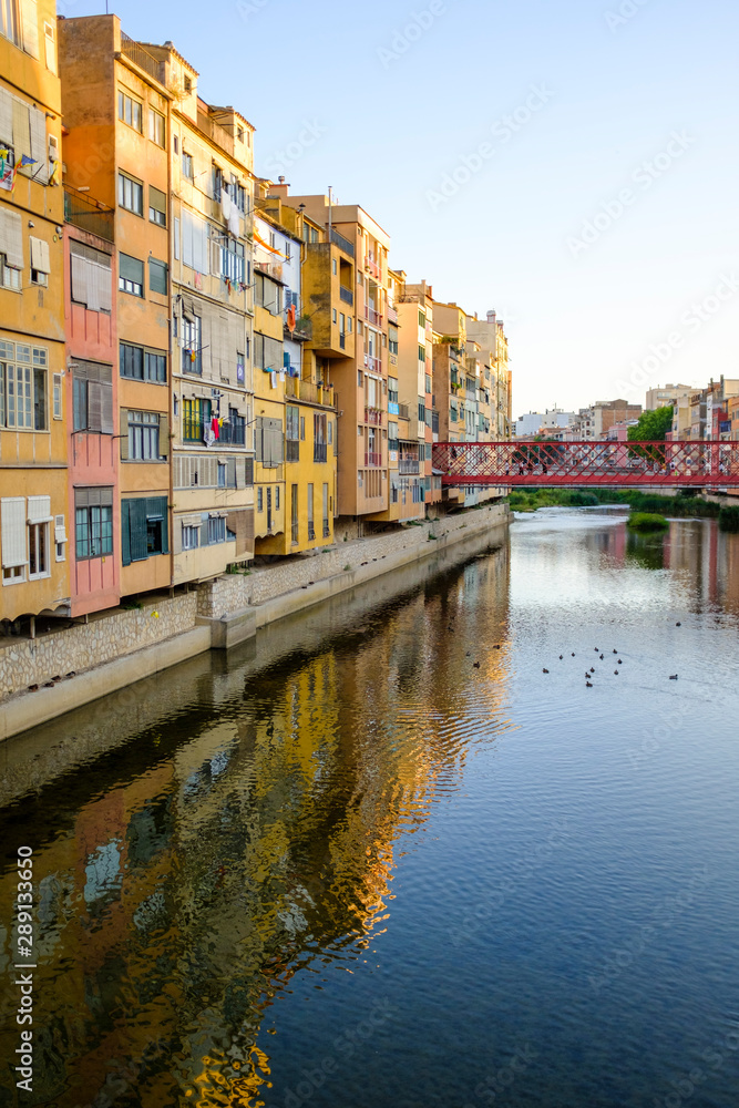 Colourful facade building landmark reflected on river water in Girona, Catalonia