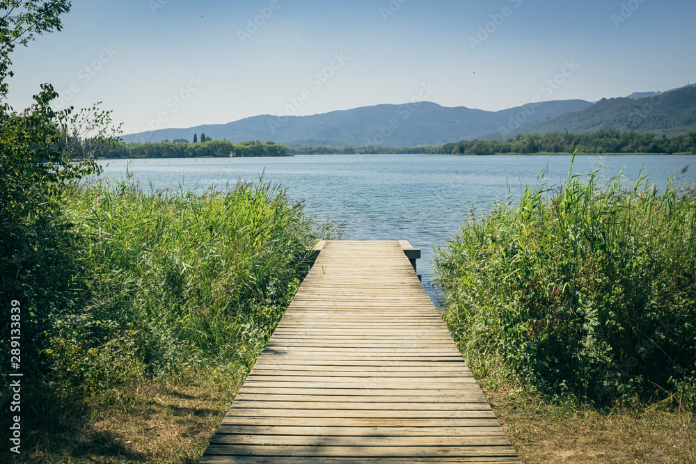 Wooden path on the shore of a blue lake in Banyoles Catalonia under a sunny blue sky on a summer landscape