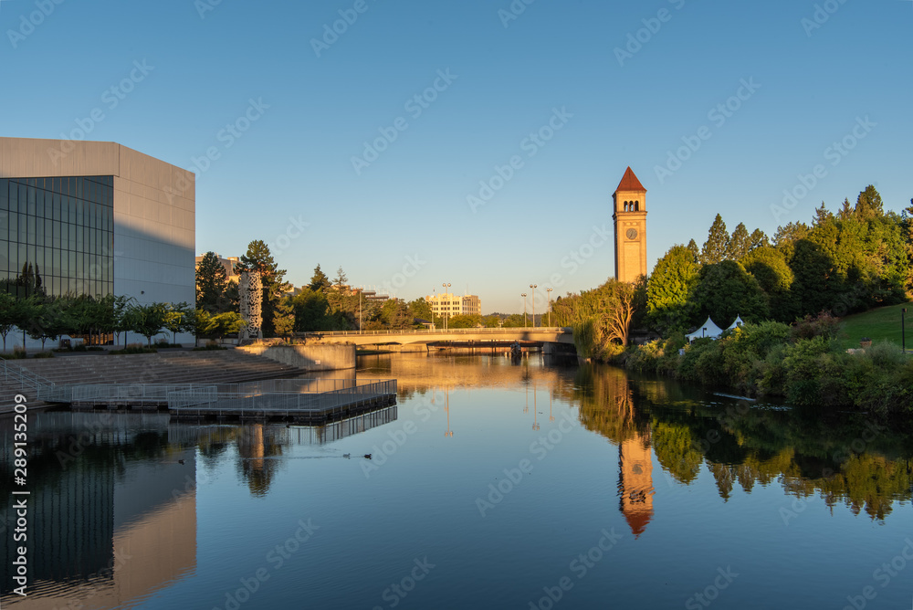 Obraz premium Golden Morning View of Reflective Spokane River Flanked by the Riverfront Park Clock Tower and the Center for the Arts