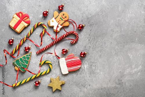 Christmas background, gingerbread cookies, candy cane and Christmas-tree decorations on a gray concrete background. Top view, flat lay. © Yulia