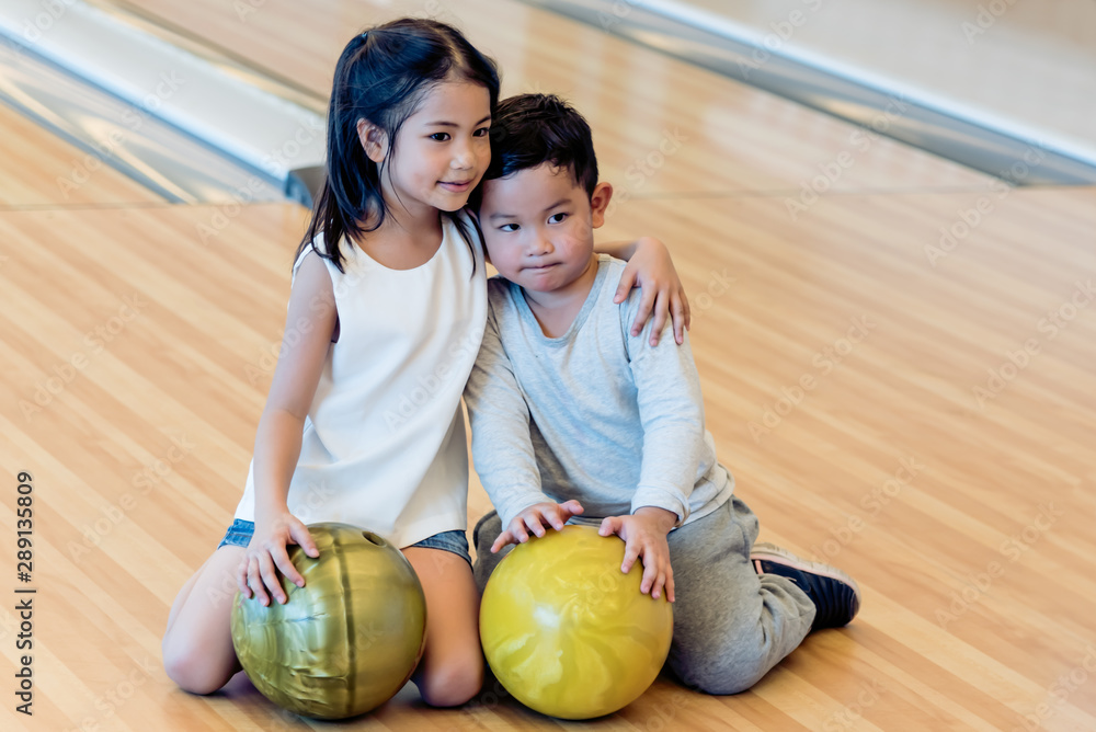Fototapeta premium Portrait images of Asian sisters and brothers sat on the bowling alley, to childrens and sports concept.