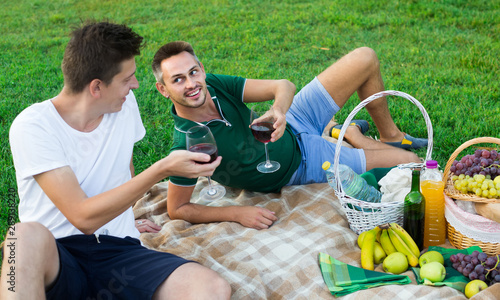 Two males friends gaily spending time together on picnic drinking wine © JackF