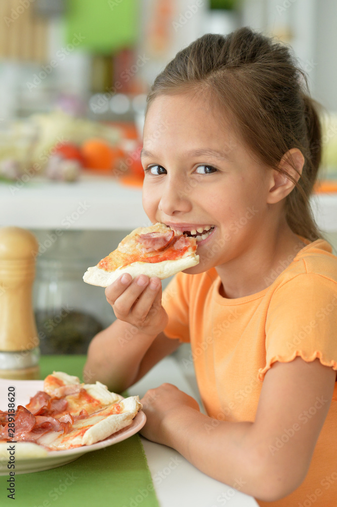 Portrait of cute girl eating pizza and posing at home