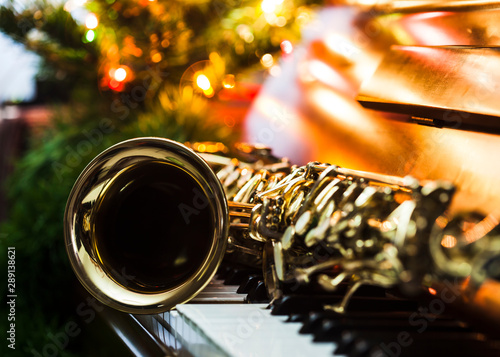 Canvas Print close up of alto saxophone  on the Piano Keys with Christmas tree and decoration