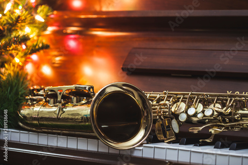 Canvas Print close up of alto saxophone  on the Piano Keys with Christmas tree and decoration