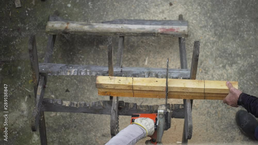 Overhead top shot of carpenter cutting piece of wood with a chain saw. Woodworker. Overhead top shot of carpenter cutting piece of wood with a chain saw. Woodworker.