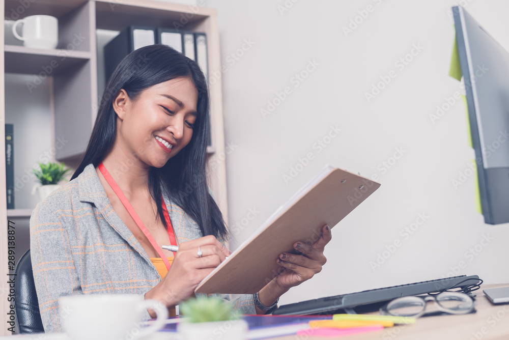 Happy female business working in office.Smiling Asian woman accountant writing on paper Happy female business working in office.Smiling Asian woman accountant writing on paper