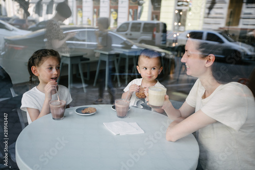 Mother with children drinking hot chocolate and latte at a local coffee shop. They are smiling and having fun. Motherhood concept