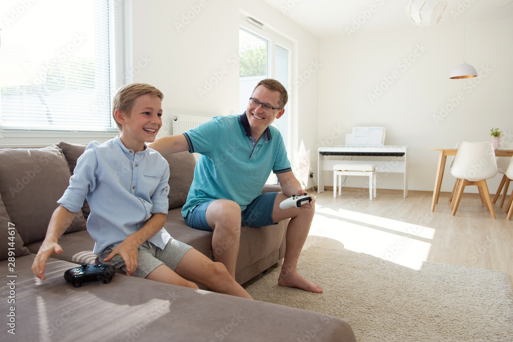 Happy young father and his son playing computer games with controllers very emotional Happy young father and his son playing computer games with controllers very emotional