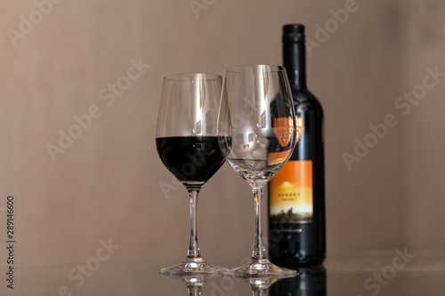 glass of red wine and bottle of wine on wooden table