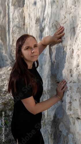 Fototapeta Naklejka Na Ścianę i Meble -  A beautiful young woman in black clothes against the white chalk mountains.