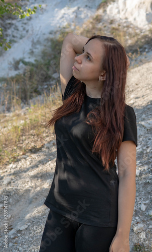 A beautiful young woman in black clothes against the white chalk mountains.