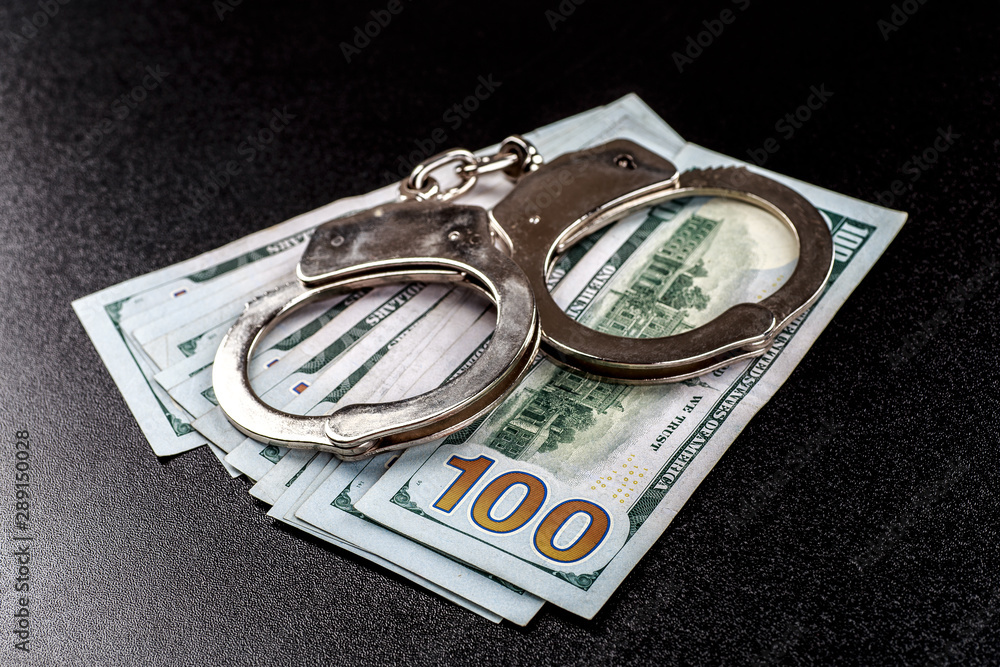 Police handcuffs. Financial crime, dirty money and corruption concept.Crime, Bribing, Fraud Police handcuffs. Financial crime, dirty money and corruption concept.Crime, Bribing, Fraud