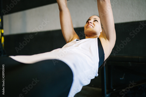 Beautiful muscular woman doing exercise with trx system