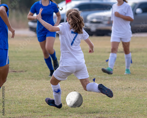 Young girl athlete playing soccer on a hot day © Joe