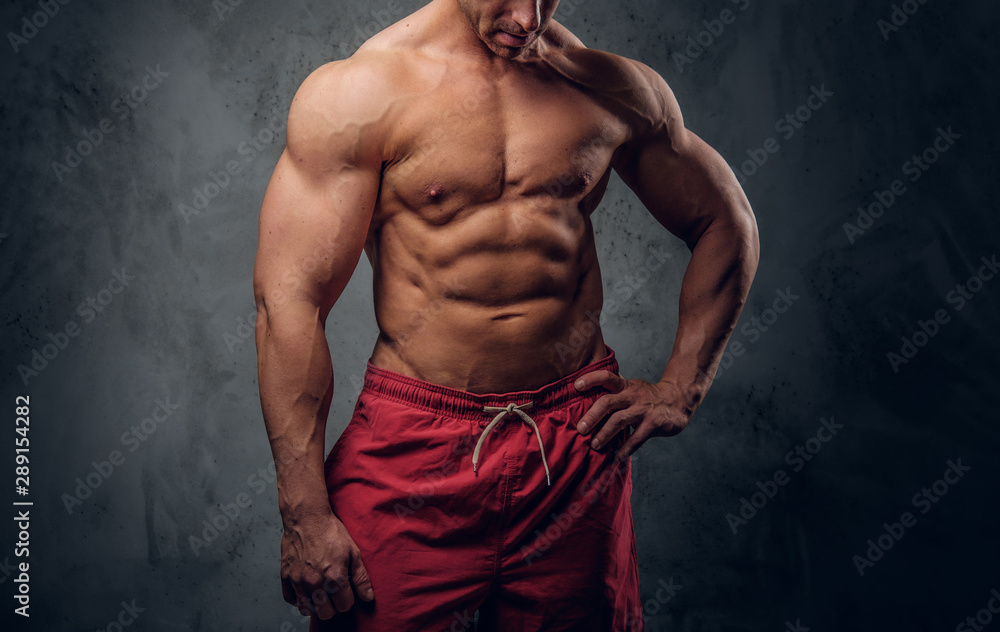 Fototapeta premium Muscular man with nice muscules is posing for photographer at dark photo studio.