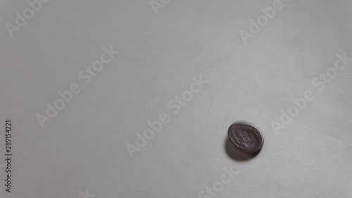 The American dime coin spins around its axis and moves from top to bottom. Heads or tails. A male hand raises a coin with the inscription Liberty on a white table.