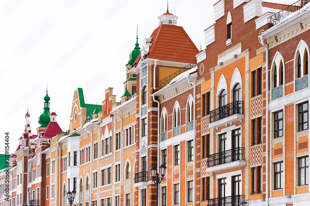 Fototapeta premium Fragment of a building wall with windows, orange kripich and white marble, Yoshkar-Ola, Russia