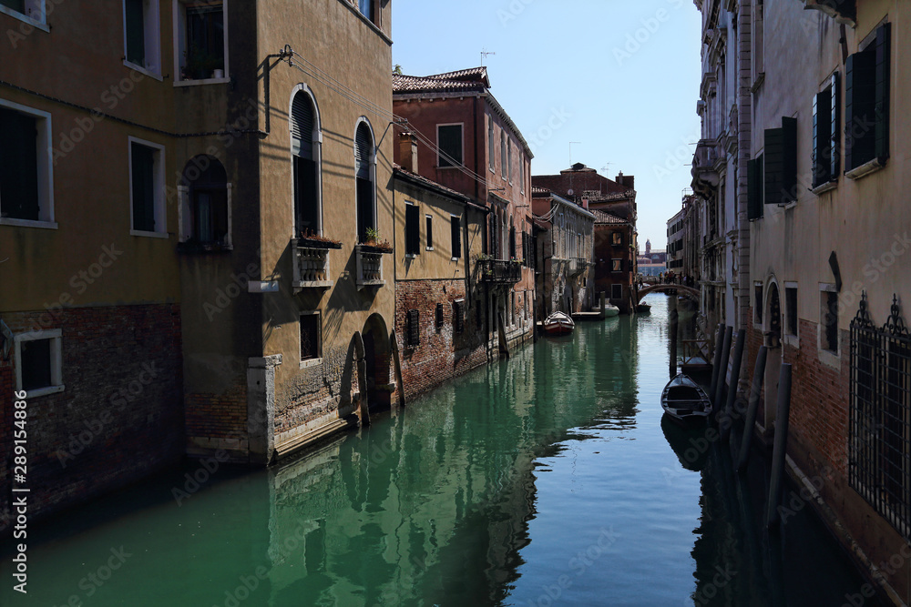 Narrow canal with small boats in Venice, Italy