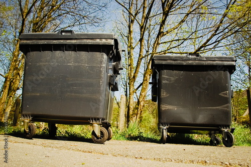 Two dumpsters in the front of a park