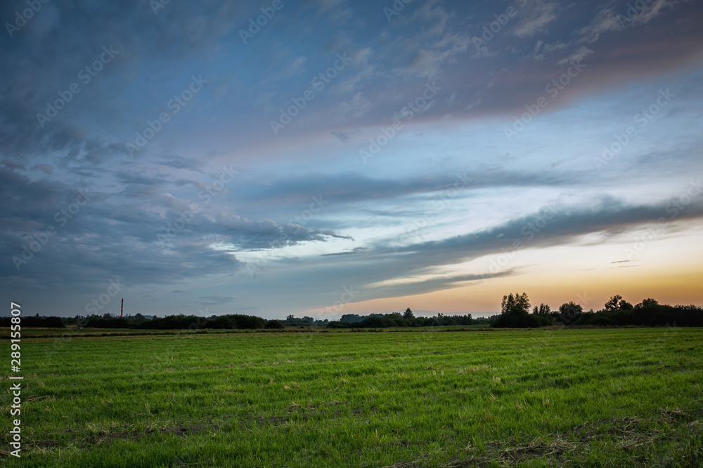 Green farmland, colorful clouds after sunset