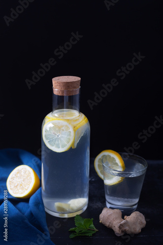 Ginger Water in a Glass Bottle With Lemon and Honey on a Black Background