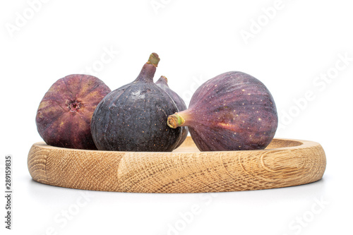 Group of three whole velvety fresh fig fruit on bamboo plate isolated on white background photo