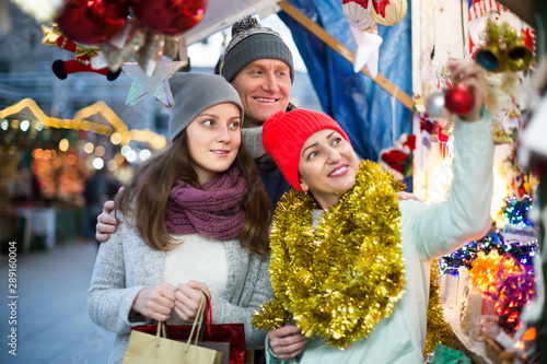 glad married couple with a teenage daughter at Christmas market