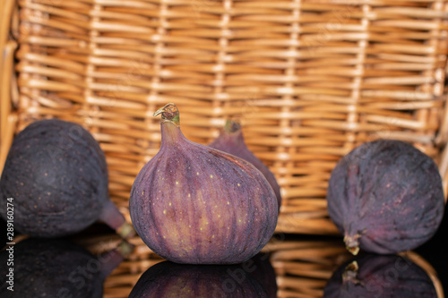 Group of four whole fresh fig fruit with braided rattan behind photo