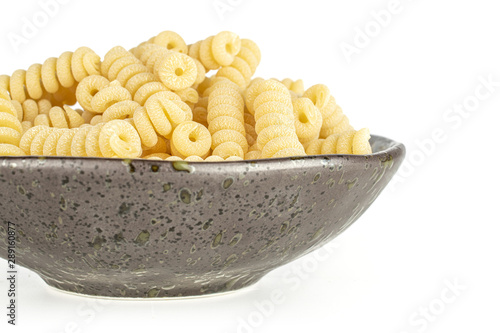 Lot of whole fresh raw pasta fusilli bucati on grey ceramic plate isolated on white background
